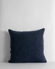 A deep blue cushion with a textural weave and a subtle lustre