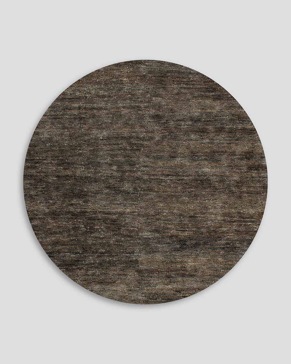 A full image of the Fairbanks floor rug in round, an effortlessly luxurious bamboo silk and jute blend. The warm brown of the jute blends with the soft greys of the silk, adding texture and interest. 