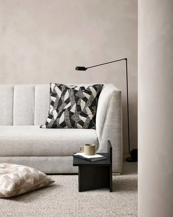 The Baya black abstract patterned cushion on a couch in a contemporary lounge room