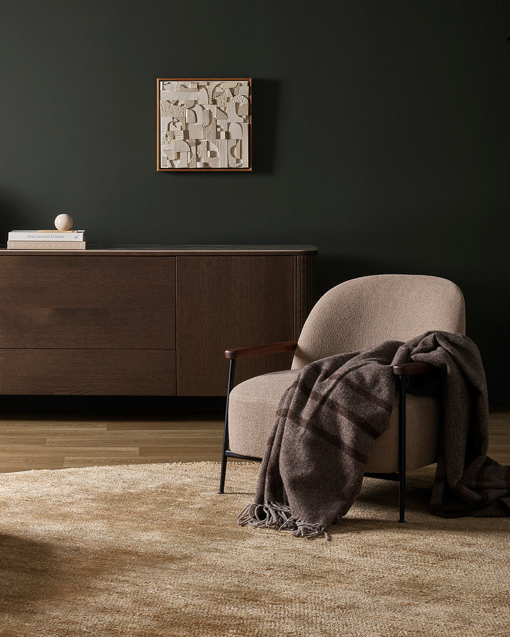 Modern interior with a chair draped with a brown wool throw blanket, a cabinet, and a rug