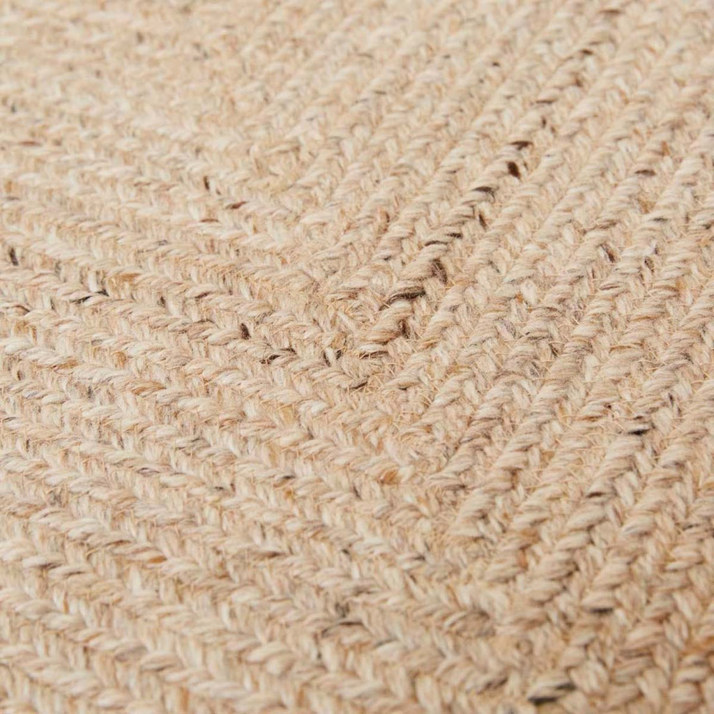 A close up of a braided rug by Globe West and Soren Liv NZ in natural beige tones, perfect for outdoors or transition spaces. 