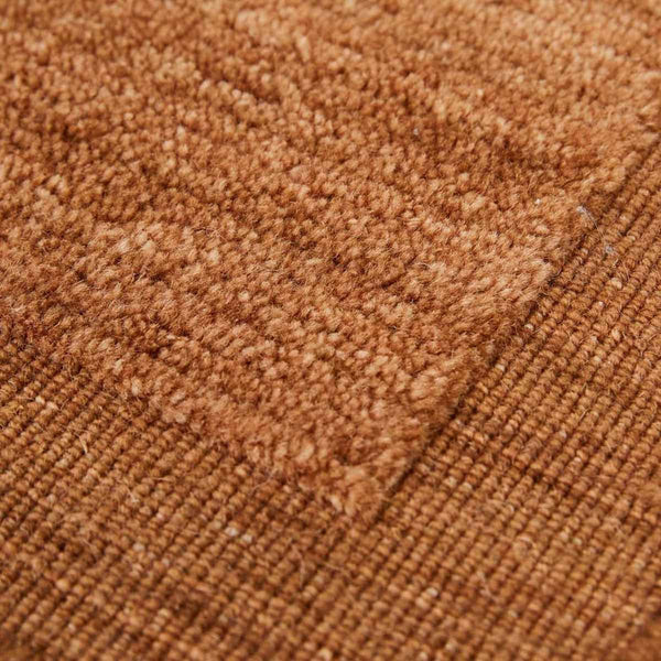 A close up of a handmade 100% wool rug by Globe West and Soren Liv NZ in a rich rust brown colour, with an indented border adding interest. 