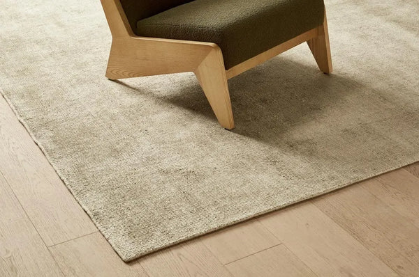 A silvery grey wool blend rug, seen in a modern room under a chair in warm light