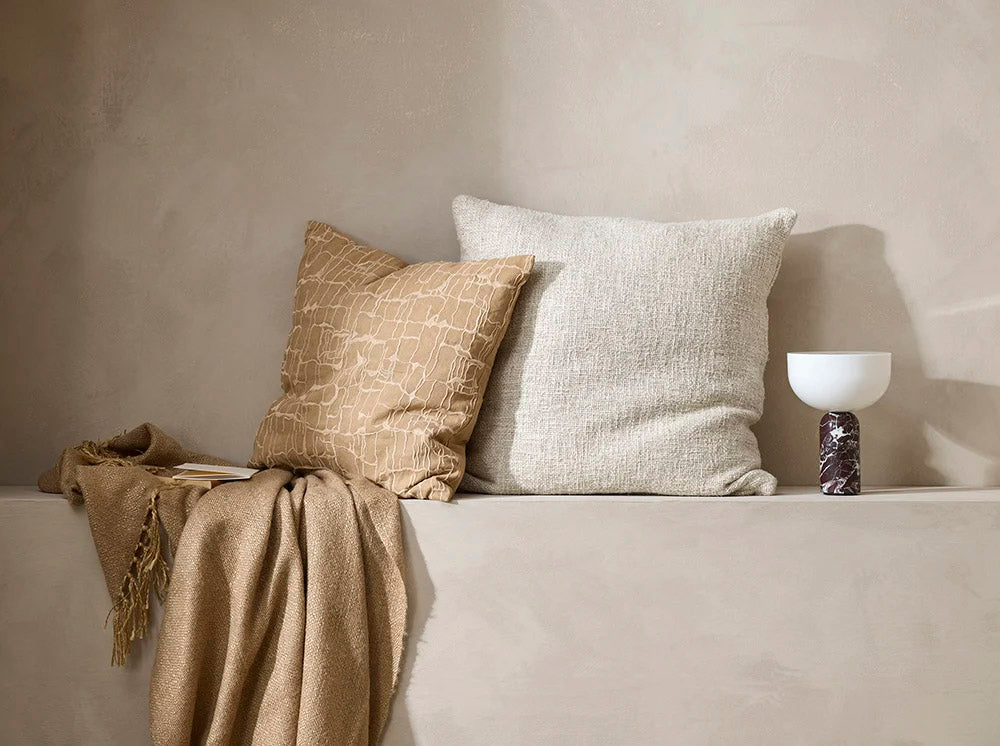 Brown patterned 'Triton' cushion, with the cream 'Cyprian' cushion and nid brown throw blanket in a modern home