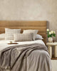 Baya designer cushions in natural linen-look and beige or taupe tones, inspired by Japanese design, seen together on a comfy looking modern bed, in a stylish bedroom.