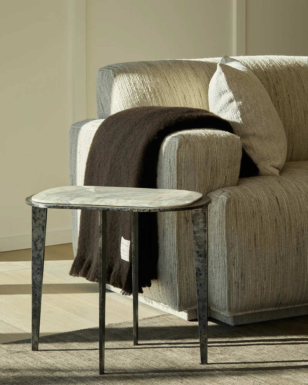 A deep chocolate brown throw blanket draped over the arm of a couch. 