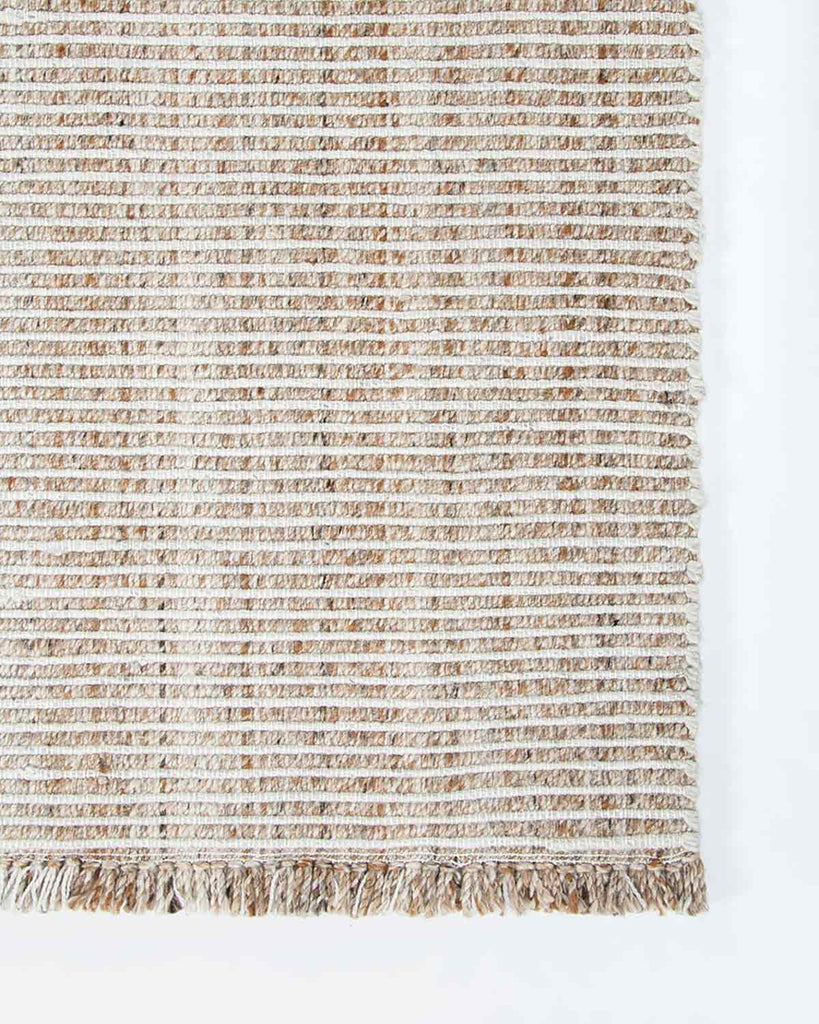 The Rhodes outdoor rug in brown and cream tones, seen at the corner from above to highlight the elegant weave
