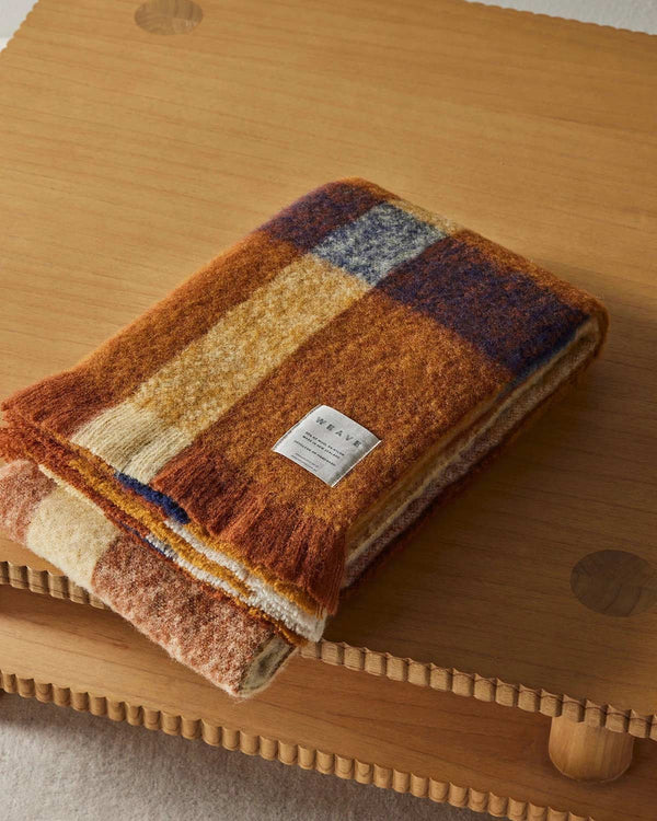 A folded orange check patterned wool throw blanket. 