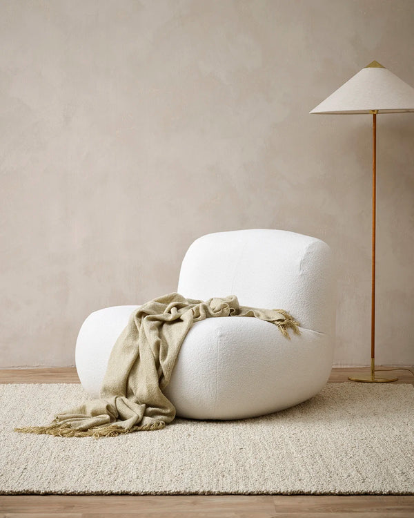 The Baya 'Richmond Putty' throw blanket, draped over a chair in a modern living room