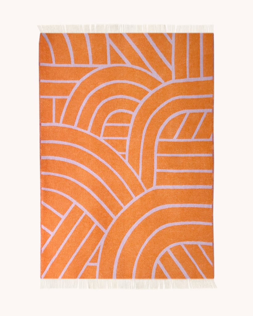 A full view of the reverse side of the Maison Deux NZ wool throw blanket with a lined pattern, in shades of mostly orange with pale purple detailing.