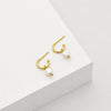 A pair of gold hoop earrings with freshwater pearl charms. 