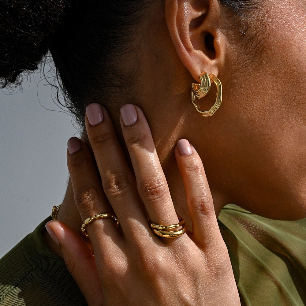 A woman wearing an assortment of chunky gold-plated jewellery by Linda Tahija. 