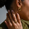 A woman wearing an assortment of chunky gold-plated jewellery by Linda Tahija. 