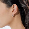 A woman wearing a sterling silver huggie hoop earring. 