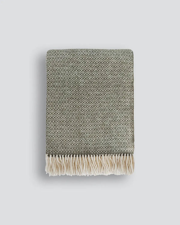 The Baya 'Kale' dark green wool throw blanket with fringe, folded tidily