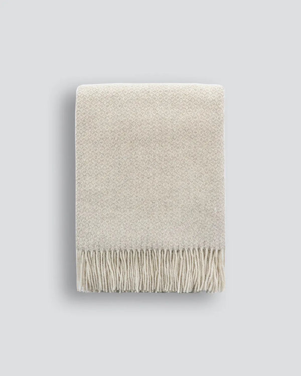 The Baya wool throw blanket 'Littano' in coloour cream oatmeal - folded with fringe showing