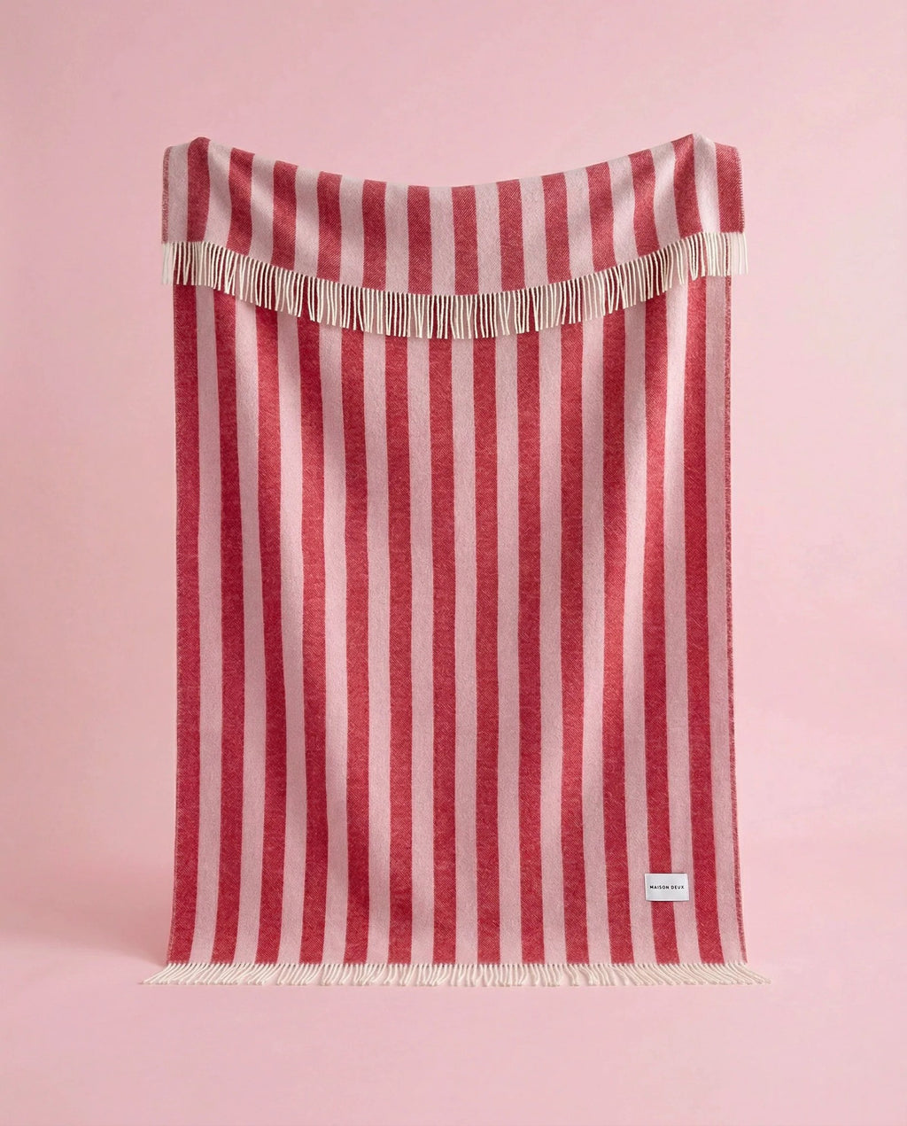 Maison Deux Candy Wrap wool throw in Pink Cherry, hanging to show the full striped pattern.