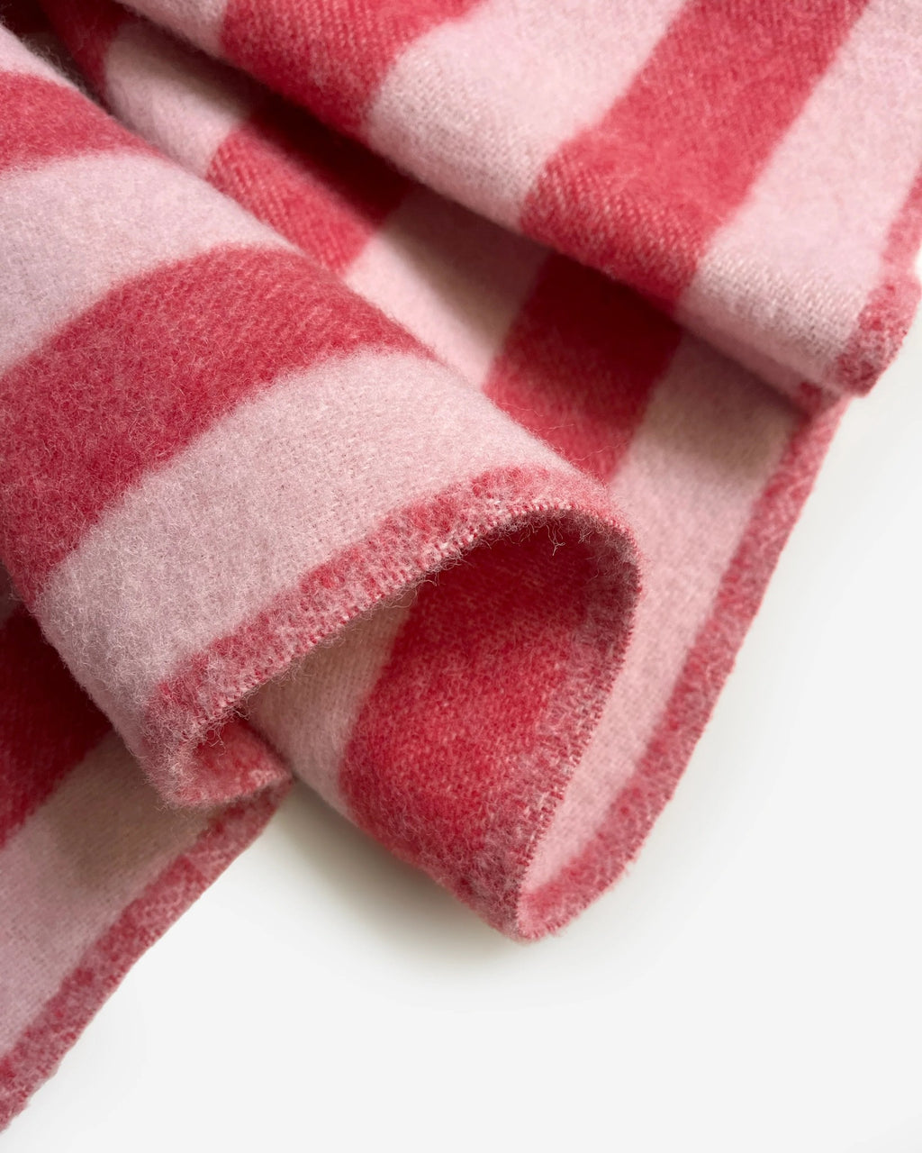 Maison Deux Candy Wrap wool throw in Pink Cherry, folded to show the woven brand label and fringe.