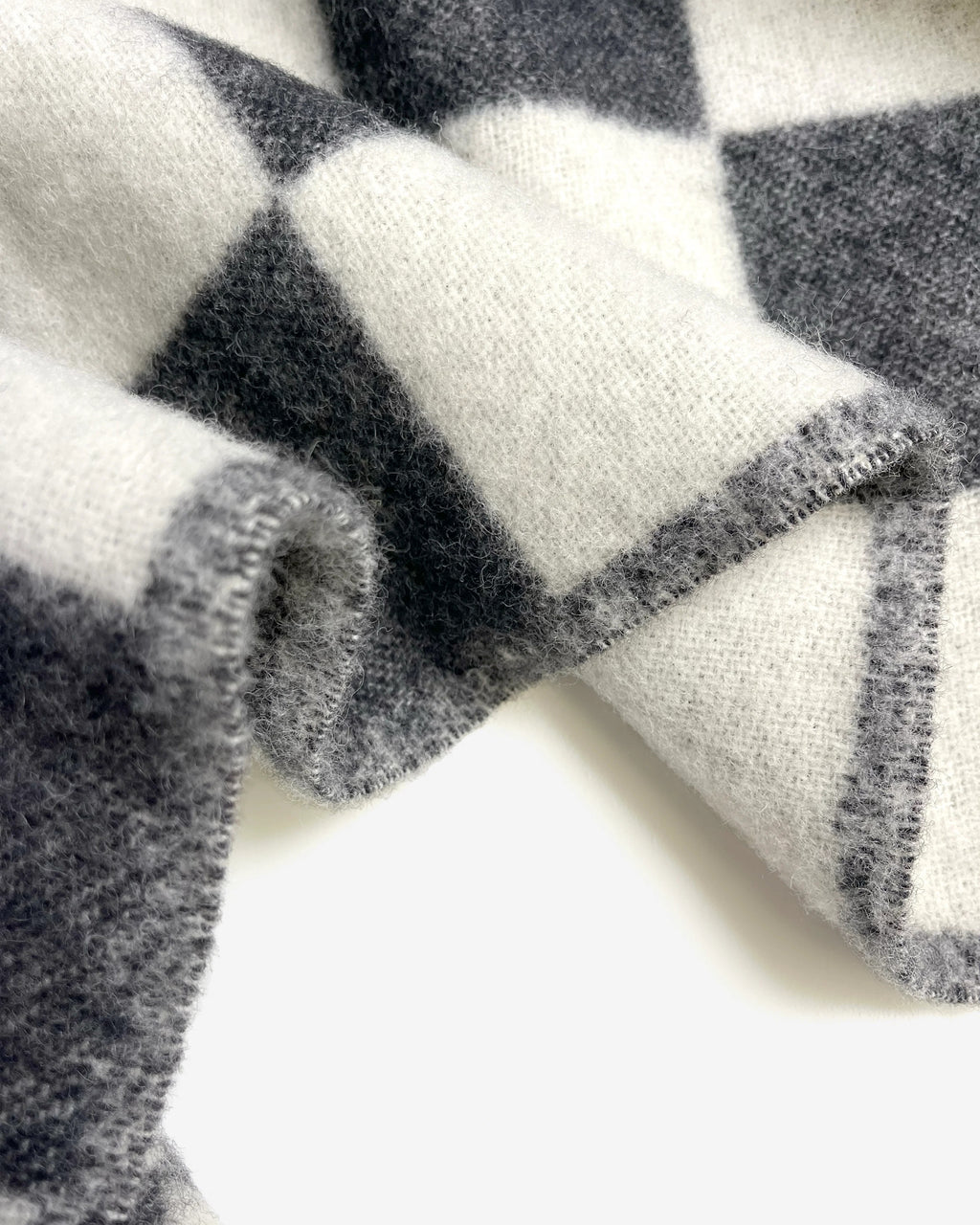 Close-up of the Maison Deux Checkerboard wool throw in Black White, showing the jacquard weave and folded edge.