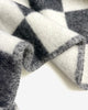 Close-up of the Maison Deux Checkerboard wool throw in Black White, showing the jacquard weave and folded edge.