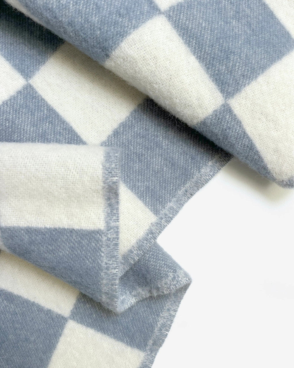 Close-up of the Maison Deux Checkerboard wool throw in Denim White, showing the jacquard weave and folded edge.