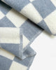 Close-up of the Maison Deux Checkerboard wool throw in Denim White, showing the jacquard weave and folded edge.