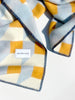 Maison Deux Cubics wool throw in Blue Honey, folded corner detail showing the navy blanket stitched edge and the woven Maison Deux label