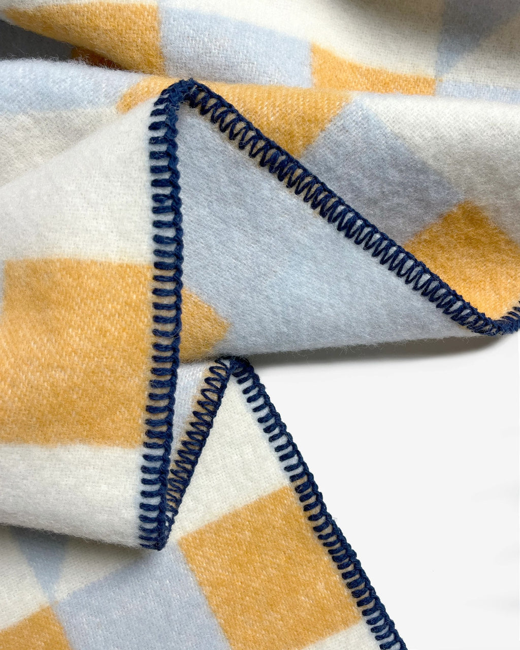 Maison Deux Cubics wool throw in Blue Honey, close up on the jacquard weave and navy blanket stitched edge