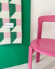 Maison Deux Cubics wool throw in Grass Pink, draped beside a pink chair against a green wall