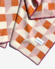 Maison Deux Cubics wool throw in Pink Carrot, folded corner detail showing the raspberry blanket stitched edge and the woven Maison Deux label