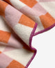 Maison Deux Cubics wool throw in Pink Carrot, close up on the jacquard weave and raspberry blanket stitched edge