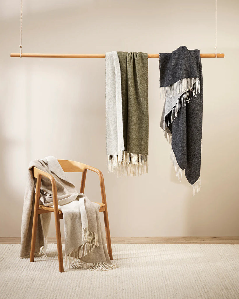 Three designer throw blankets in neutral tones shown draped in various ways
