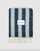 A folded large wool throw with navy and ice blue stripes, with a cream fringed edge. 