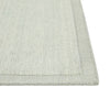 Close up of the corner of a handmade, 100% wool floor rug by Soren Liv NZ and Globe West, in subtle shades of light blue and green, shades of seafoam. The edges of the rug are indented, lending subtle sophistication.