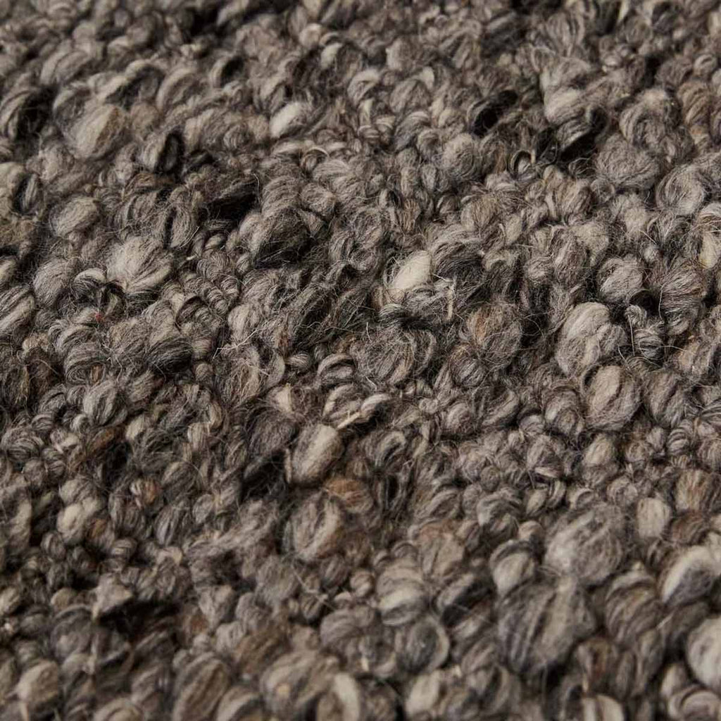 Close up of the weave of a textural wool blend boucle style rug by Globe West and Soren Liv NZ in shades of grey and charcoal.