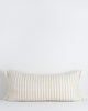 A lengthy cotton lumbar cushion, with regular vertical blue stripes across a cream background. The cushion is fringed at the edges, which adds softness and sophistication. By Baya