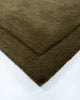 The corner of the Norfolk rug in Olive by Baya. The minimalist cut-pile border adds interest to this stunning piece. 