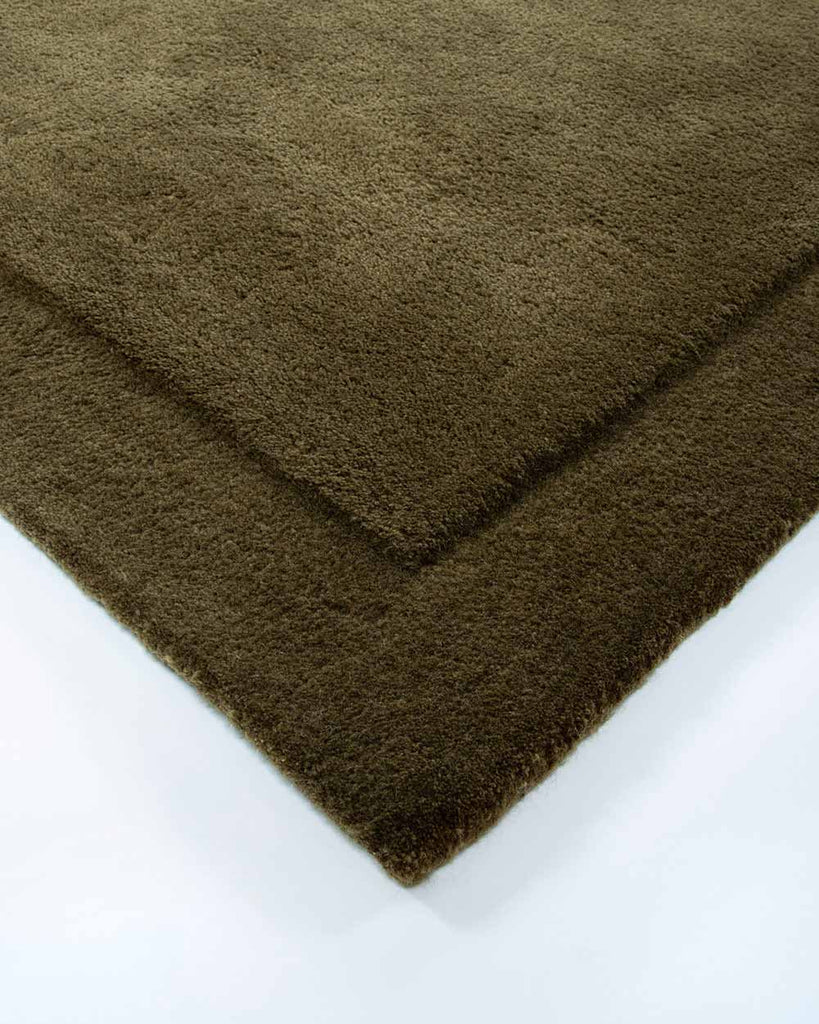 The corner of the Norfolk rug in Olive by Baya. The minimalist cut-pile border adds interest to this stunning piece. 