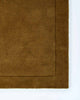 The corner of the Norfolk floor rug in the shade Brass. The border of the rug is cut-pile in a minimalist and refined design. 
