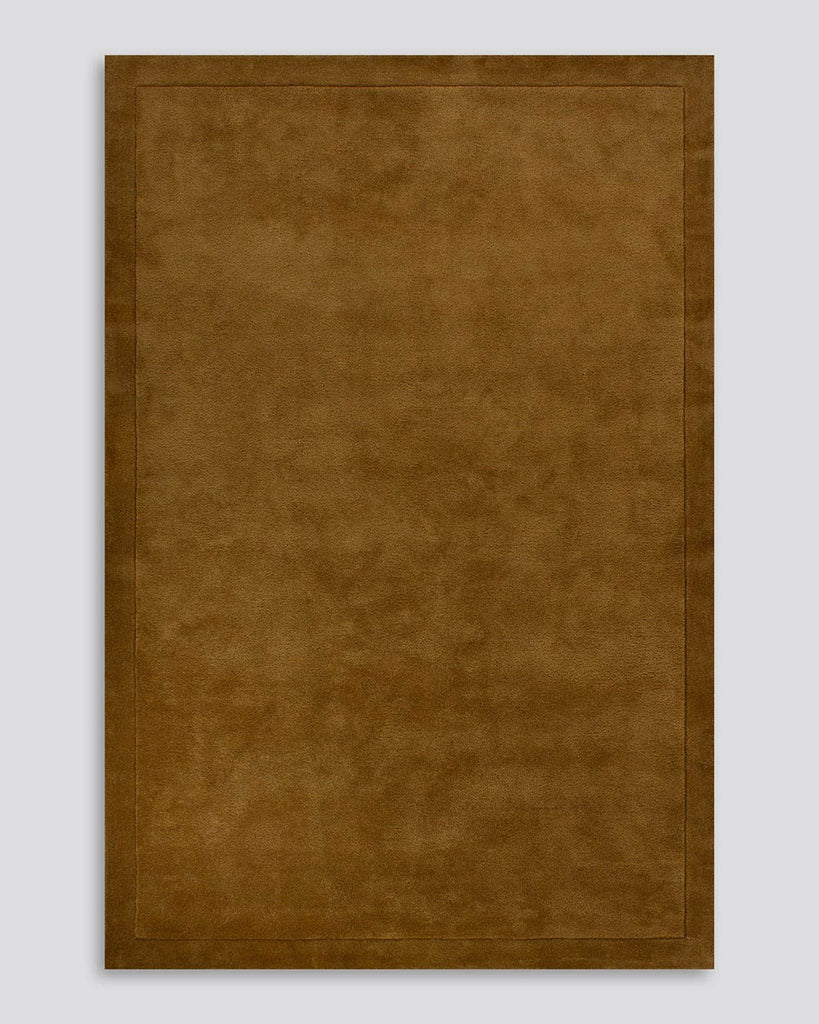 A full image of the Norfolk floor rug in the shade Chocolate. The border of the rug is cut-pile in a minimalist and refined design, and the pile of the rug's centre is luxuriously deep.
