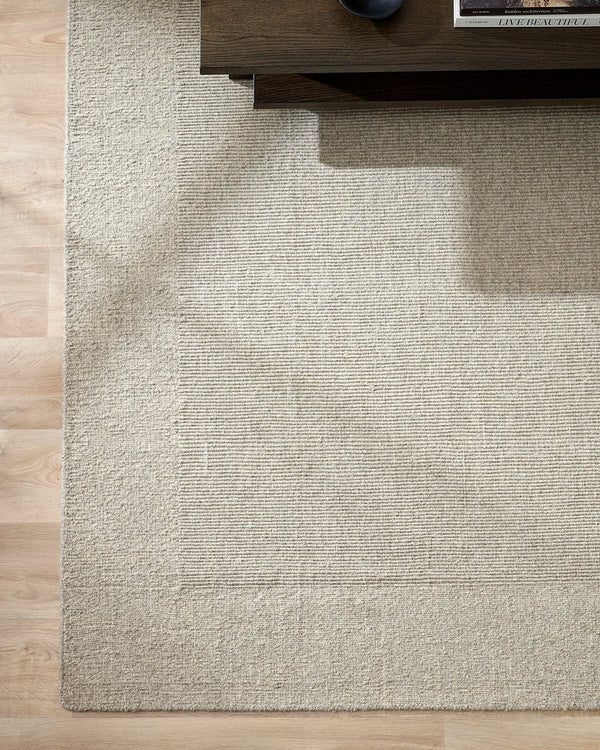 Corner of the Baya 'Vermont' wool floor rug in colour 'Driftwood' from above on wooden floor