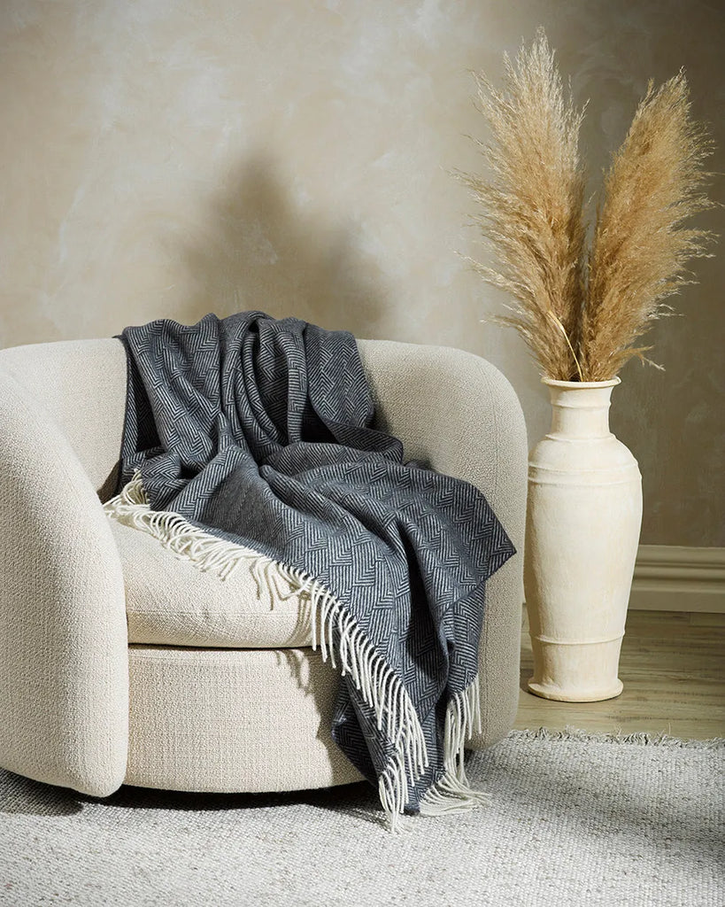 The Baya Lana throw blanket in navy blue, draped over a chair in the contemporary lounge room