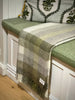 Pure nz wool throw blanket, by Exquisite Wool Traders, in olive green and white plaid shown folded on a window seat