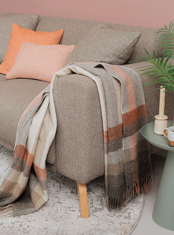 NZ wool throw blanket in white rust and brown tones, draped over a couch in a contemporary living room