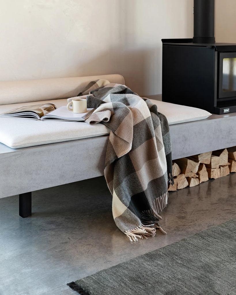Nz made wool throw blanket in a modern plaid featuring blush browns, black and cream, in a stylish home