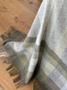 Pure nz wool throw blanket, by Exquisite Wool Traders, in olive green and white plaid shown draped