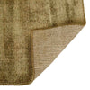 Close up of the corner of a soft, wool blend rug in shades of muted olive green by Soren Liv NZ and Globe West. The edge of the rug is flipped up to reveal the underside. 