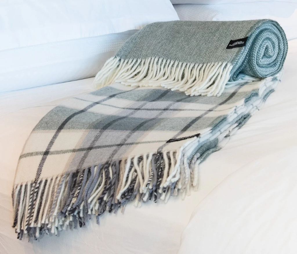Palliser Ridge Herringbone throw in Forest, rolled and styled on a bed