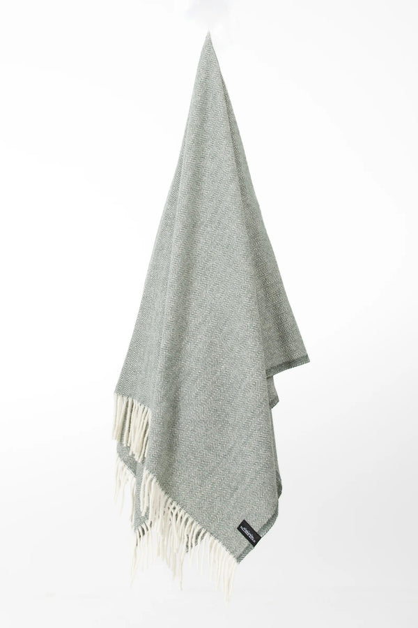 Palliser Ridge Herringbone throw in Forest hanging in full drape, showing the fringed edge