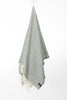 Palliser Ridge Herringbone throw in Forest hanging in full drape, showing the fringed edge